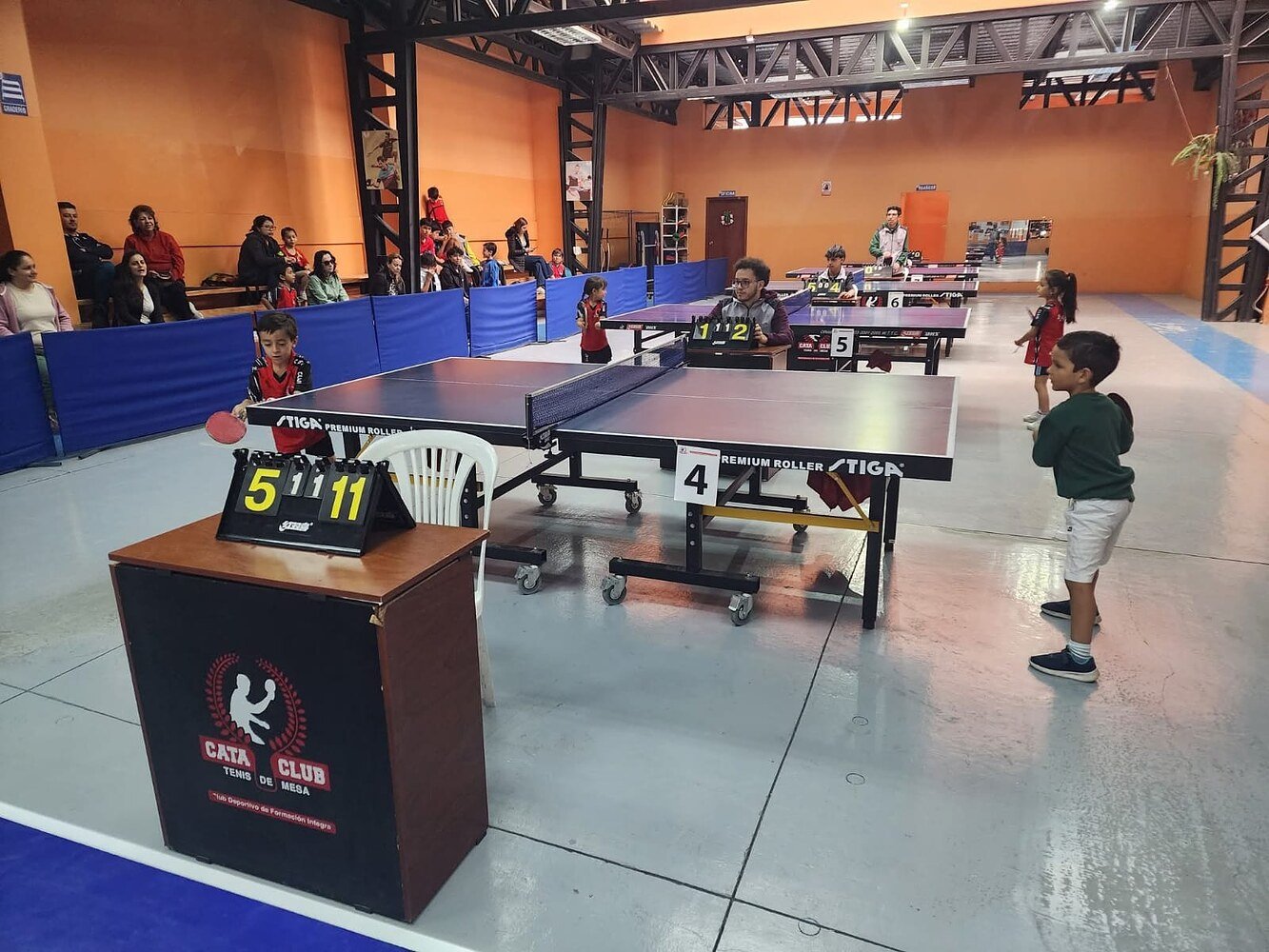 Vista general del gimnasio con varias mesas en juego durante un torneo